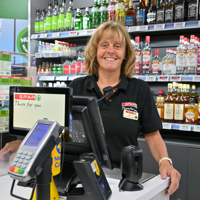 SPAR store staff member standing by a till.